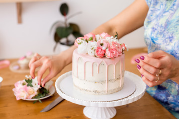 close-up of women's hands decorating the cake with fresh flowers..