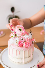 close-up of women's hands decorating the cake with fresh flowers..