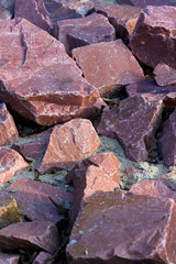 Natural background with red chipped stones. Red crushed stone on the ground close-up.