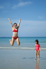Fototapeta premium Asian chinese woman spending time playing with daughter at the beach