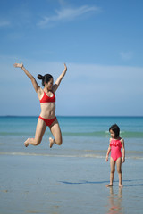 Asian chinese woman spending time playing with daughter at the beach
