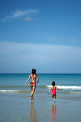 Asian chinese woman spending time playing with daughter at the beach