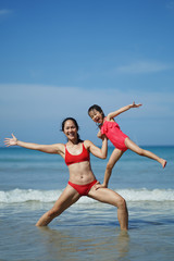 Obraz premium Asian chinese woman spending time playing with daughter at the beach