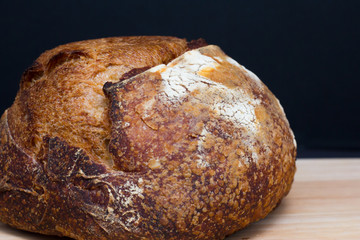 A traditional baked sourdough bread with crust on a wood cutting board