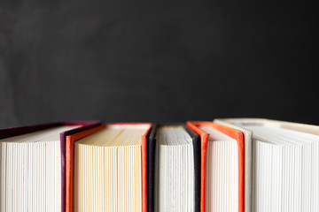 Stack of books with selective focus on black background with copy space. Banner format. Home education, learning and studying
