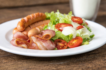 Close-up Bacon, Sausage, Salad with milk on wooden table background.