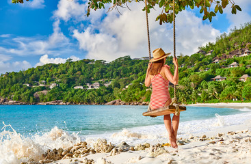 Woman swinging at tropical beach, Seychelles.
