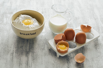 Ingredients for making breakfast on a white wooden table: a cup with the inscription 