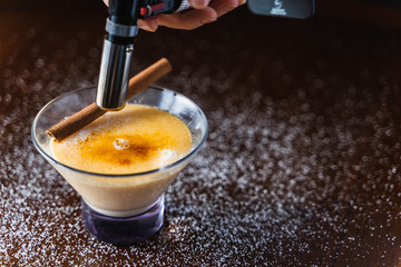 Chef burning sugar on top of a cream in a crystal glass