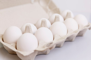 White chicken eggs in an eco-friendly paper container. Healthy diet food. Close-up. White background. Space for text.