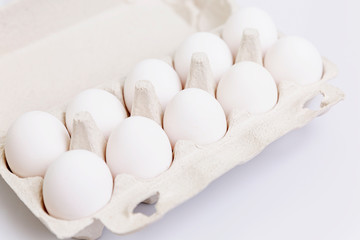 White chicken eggs in an eco-friendly paper container. Healthy diet food. Close-up. White background. Space for text.