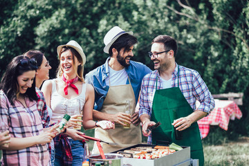 Barbecue party. Group of people standing around grill, chatting, drinking and eating.
