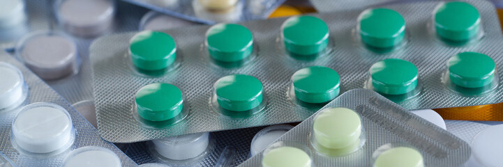 heap of multi-colored round tablets in blisters lie on the table