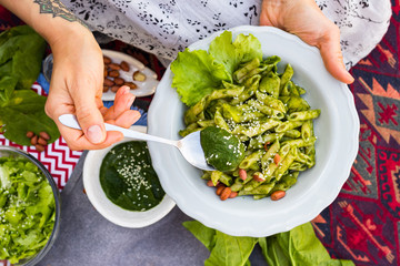 Italian pasta with green basil pesto sauce. Vegan healthy food. Woman hands