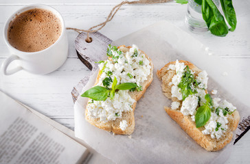 sandwiches with soft cheese and Basil, a Cup of black coffee, a book of herbs on a white wooden background, Breakfast,