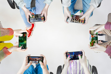 Hands of people playing multiplayer online games with friends on phones while sitting in a bright...