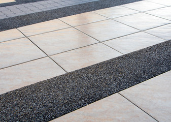 The different surface texture of the different flooring materials on the building sidewalk