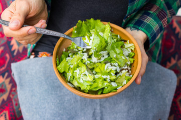 Long white basmati rice fresh green asian salad with lettuces leaves. Vegan healthy food. Wooman hands
