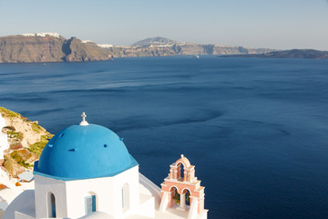 Famous blue dome churches in Oia, (Santorini, Greece) in the morning. White architecture of Oia village on Santorini island, Greece. Traditional tourism in mediterranean white architecture view