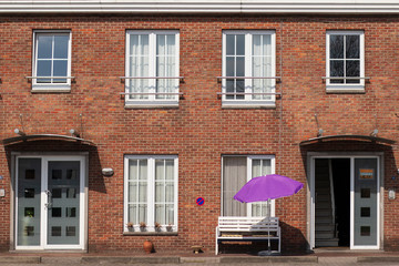 symmetric facade of an old building with a purple umbrella