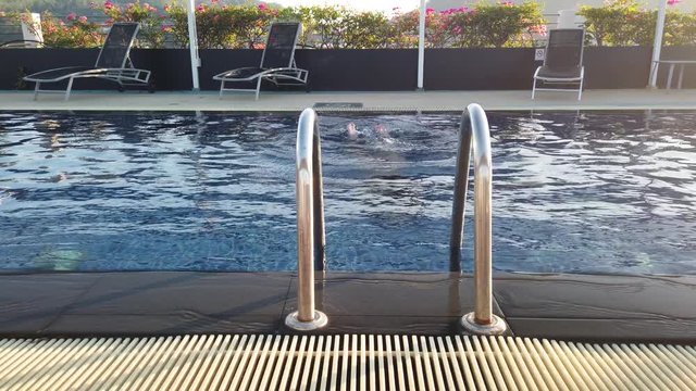 The girl swims in the hotel pool. Girl relaxes by the pool