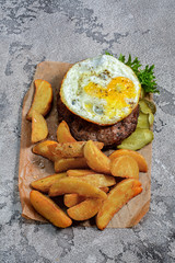 Steak with fried eggs and potato slices