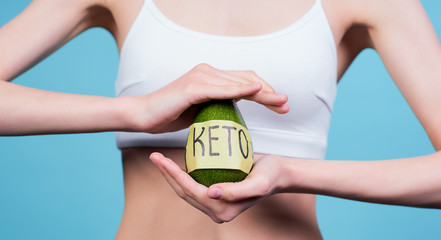 Cropped frame, the girl on the keto diet keeps the avocado. - obrazy, fototapety, plakaty