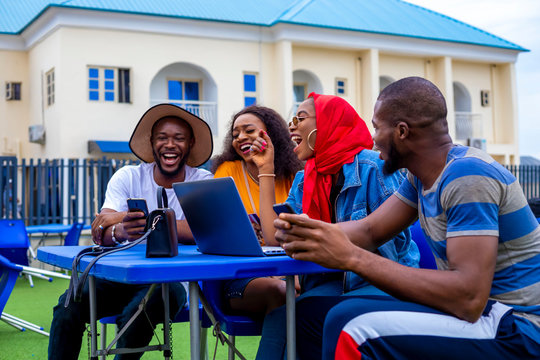 Young Black Friends Sitting Out, Having Fun And Using A Laptop