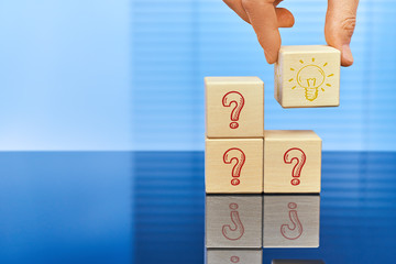 The concept of finding the optimal idea. Three cubes have question marks on a blue background, and...