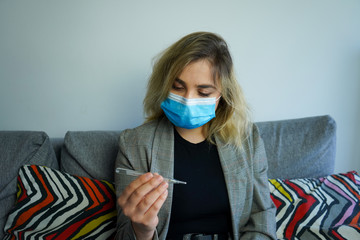 European woman checking high temperature with thermometer. Corona virus infection symptoms headache...