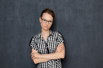Portrait of serious focused woman with glasses, holding arms folded