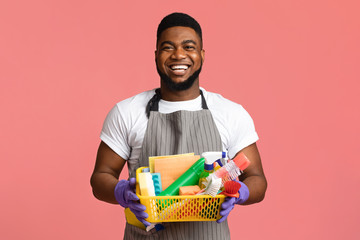Portrait of positive black man holding basket with cleaning tools