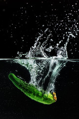 Green cucumber falls into the water