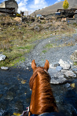 Obraz premium Rear view of a horse crossing a river to enter the village of Dartlo