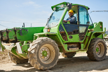 An engineer in uniform drives a green tractor.