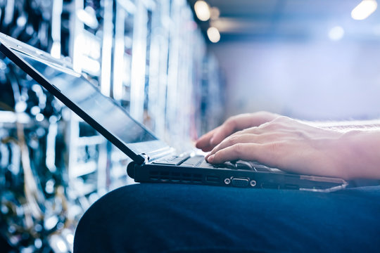 IT specialist working on computer in bitcoin and crypto currency mining farm.