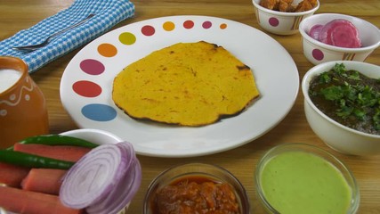 Closeup shot of woman hands serving Makki ki Roti in a designer plate - food concept. Traditional Punjabi cuisine Makki ki Roti and Sarson ka saag served with Kulhad Lassi  salad  green chutney  pi...