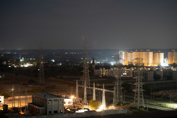 Aerial night shot of a power transformer plant with residential or office buildings in the background in Gurgaon Delhi India