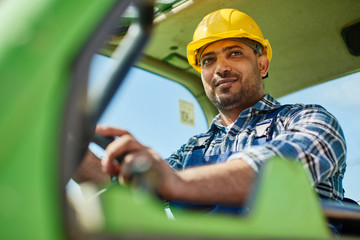 An engineer in uniform drives a green tractor.