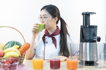 A cute girl makes vegetable juice, with carrot apple orange cranberry beetroot and mango in chef suit.