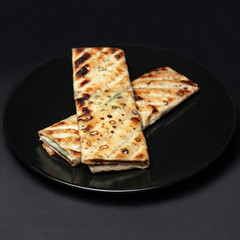 meat in pita bread on a black plate on a black background.