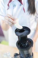 A cute girl makes vegetable juice, with carrot apple orange cranberry beetroot and mango in chef suit.