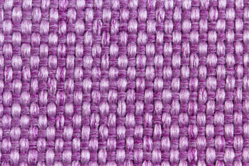 Abstract background from upholstery fabric of a matting for furniture in large knitting from purple, pink threads in macro, empty template. Gunny. Large weaving of threads on the fabric.