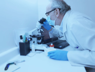 Researcher in the microbiology laboratory with a computer and a microscope