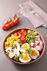 vegetable salad bowl with tomato, egg, corn, radish and pea- buddha bowl