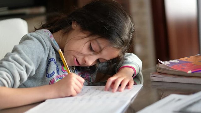 Seven years old cute girl doing homework at home alone