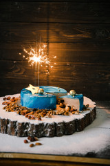 cut mousse chocolate cake with nuts space view with sparklers on a wooden slice on a black wood background