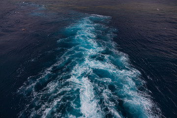 wake in blue water leaving port of Savona, Italy