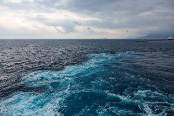 wake in blue water leaving port of Savona, Italy