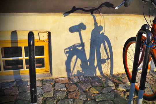 Shadow on the wall of a building from a bicycle.
